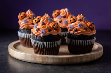 Cadılar Bayramı kekleri, siyah yüzey ve mor arka plan üzerine serpiştirilmiş.