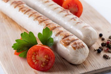 Kızarmış sosis, kiraz domatesli ve maydanozlu beyaz arka planda.