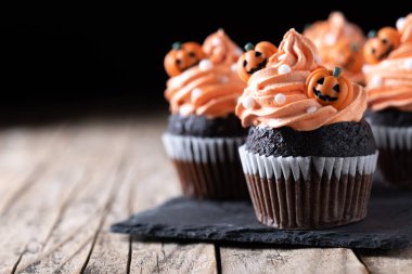 Cadılar Bayramı kekleri ve ahşap masaya serpiştirilmiş şekerler. Boşluğu kopyala