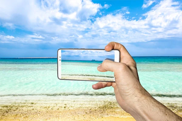 Um homem fotografa em um smartphone uma bela paisagem marinha — Fotografia de Stock