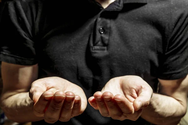 Homem em uma camiseta preta fica com as mãos estendidas — Fotografia de Stock