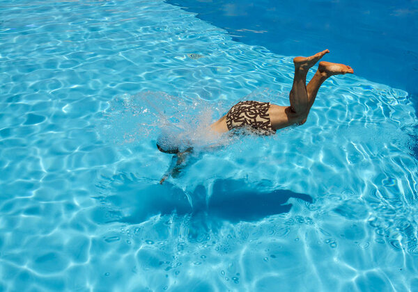 Мужчина ныряет в бассейн на курорте
 
