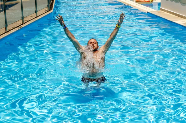 Člověk plave v bazénu na jasný slunečný den — Stock fotografie