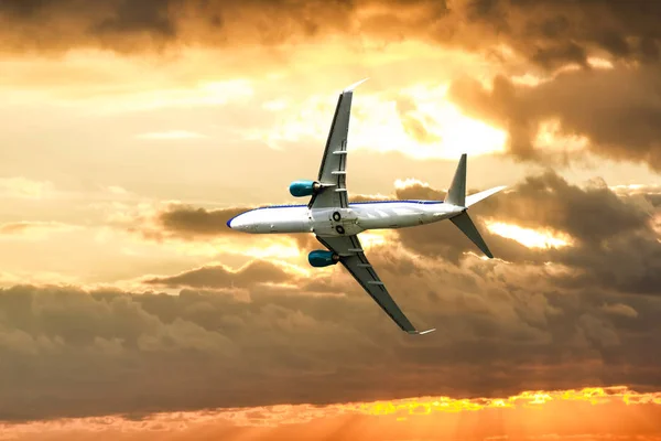 Um avião de passageiros voando no céu ao pôr do sol — Fotografia de Stock