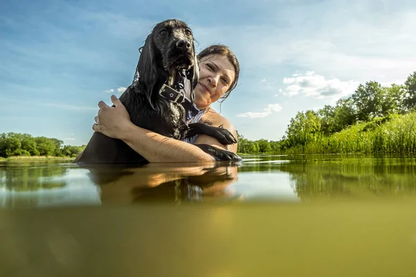 Девочка плавает в озере со своей собакой — стоковое фото