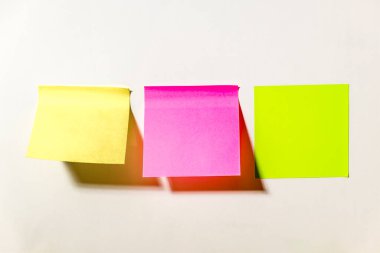 Ofisteki beyaz bir duvara yapıştırılmış çok renkli kare post-it notları