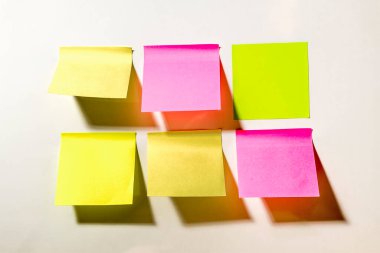 Ofisteki beyaz bir duvara yapıştırılmış çok renkli kare post-it notları
