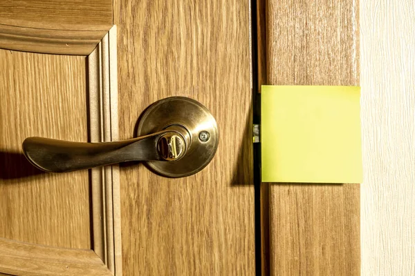 メモやリマインダーの黄色い四角形の紙がドアに貼られています — ストック写真