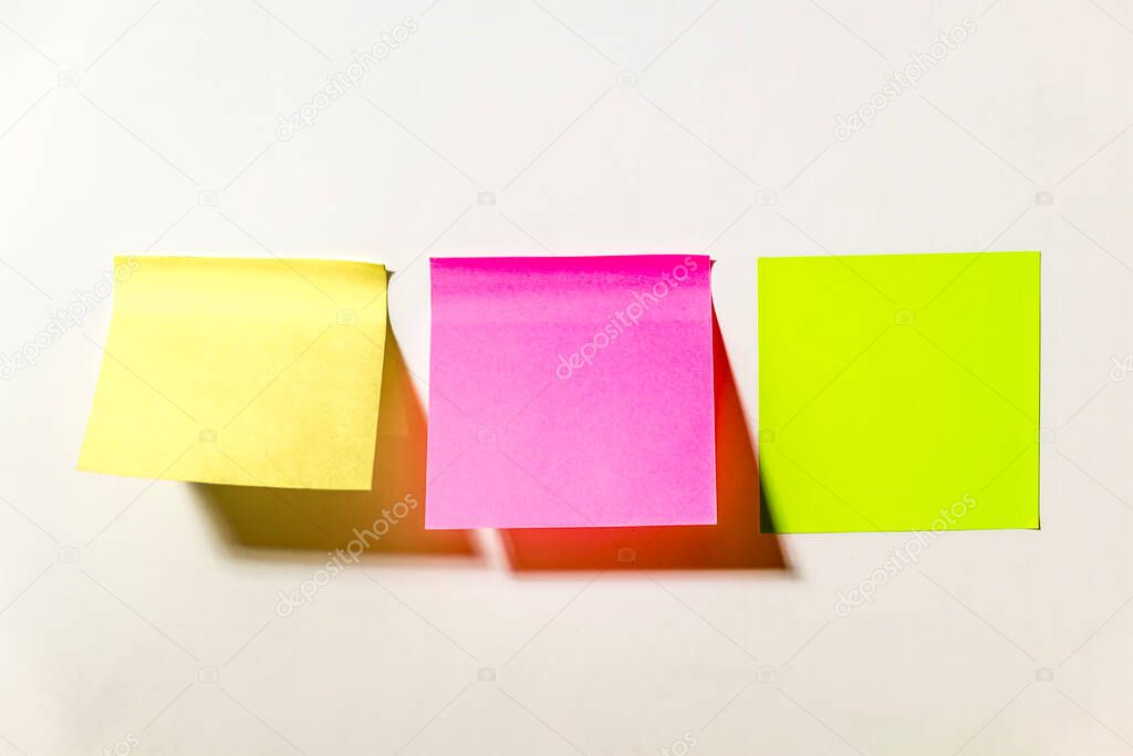 Multi-colored square post-it notes pasted on a white wall in the office