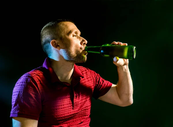 Uomo Beve Felicemente Birra Una Bottiglia Uno Sfondo Verde Scuro — Foto Stock