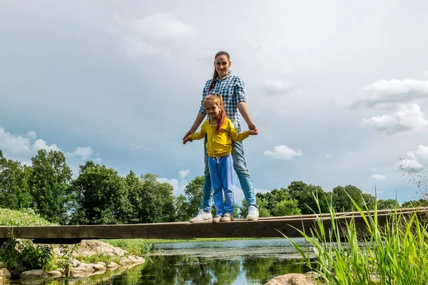 Matka Córka Stoją Moście Nad Rzeką Trzymają Się Ręce Słoneczny — Zdjęcie stockowe