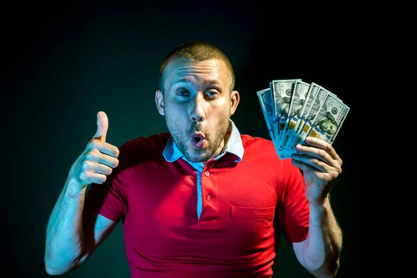 一个有着100美元钞票粉丝的快乐男人在深绿色的背景上摆出一副姿势 — 图库照片