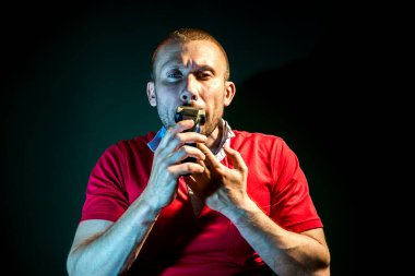 Koyu yeşil arka planda traş olan bir adam.