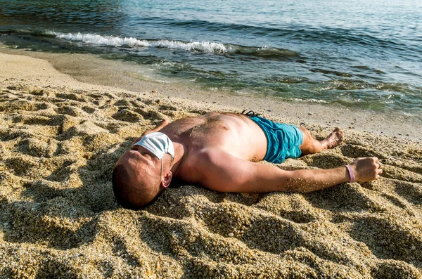 一个戴着口罩的男人在海滨度假胜地的海滩上晒黑了皮肤 — 图库照片