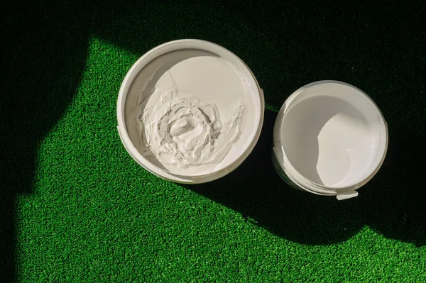 A can of white and yellow paint stands on the grass. — Stock Photo, Image