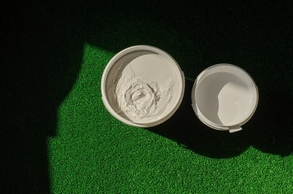 A can of white and yellow paint stands on the grass. — Stock Photo, Image