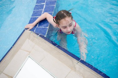 Küçük bir kız yazın su parkında dinleniyor. bebek havuzda yüzer.