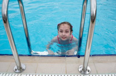Küçük bir kız yazın su parkında dinleniyor. bebek havuzda yüzer.