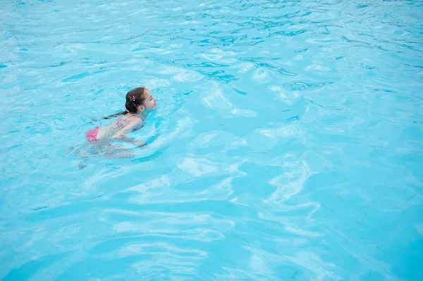 Ein kleines Mädchen ruht sich im Sommer im Wasserpark aus. Baby schwimmt im Pool. — Stockfoto