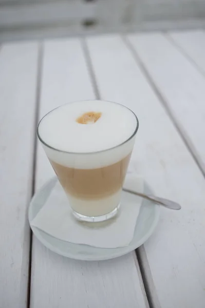 Café solárium con un café con leche en un vaso sobre la mesa . —  Fotos de Stock