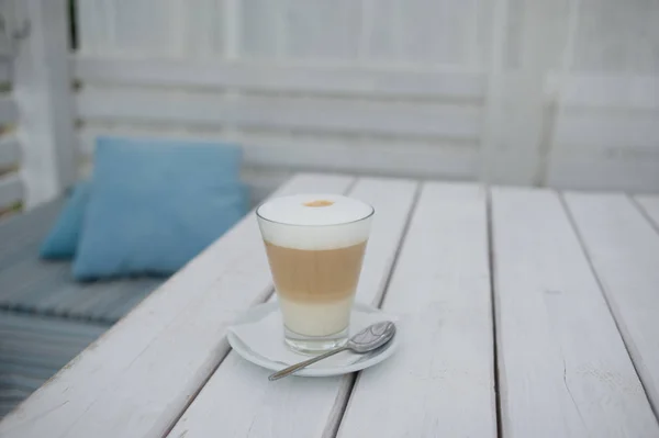 Café solárium con un café con leche en un vaso sobre la mesa . — Foto de Stock