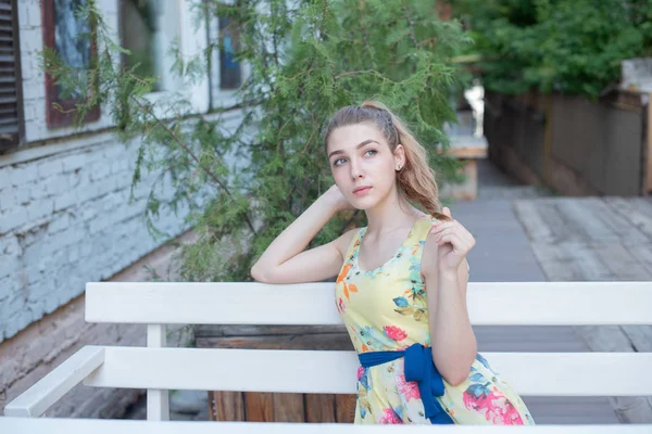Bir elbise uzun beyaz bukleler ile genç bir kız yaz aylarında eski şehir yürür. çiçek elbiseli kız — Stok fotoğraf