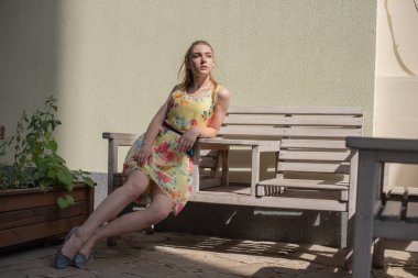 bir elbise uzun beyaz bukleler ile genç bir kız yaz aylarında eski şehir yürür. çiçek elbiseli kız