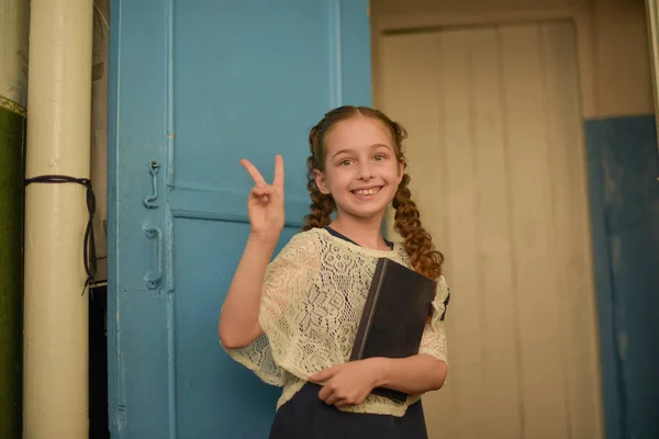 De volta ao conceito de escola e educação. A rapariga tem um grande livro aberto. Menina da escola com rosto surpreso pensando em alguma ideia . — Fotografia de Stock