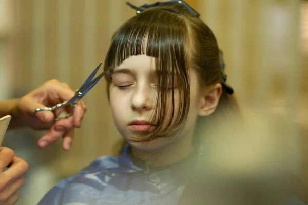 Friseur macht eine Frisur zu niedlichen kleinen Mädchen — Stockfoto