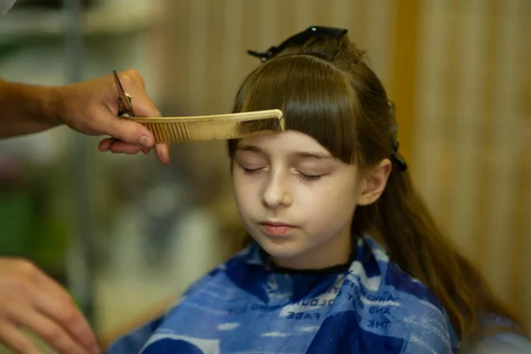 Hairdresser making a hair style to cute little girl — Stock Photo, Image