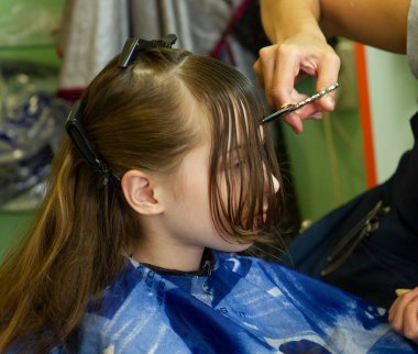 Kuaför küçük şirin kıza saç stili yapıyor.