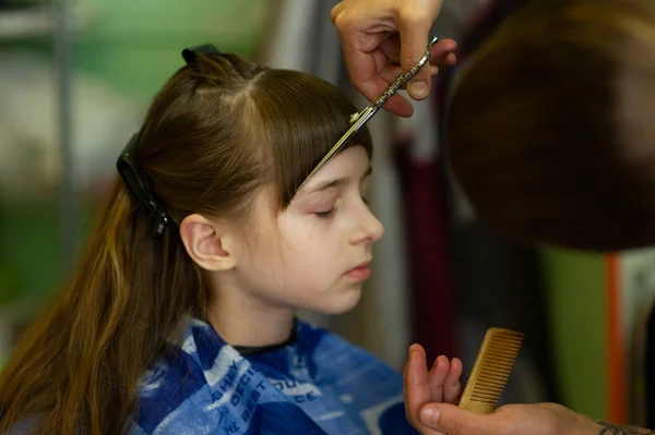 Hairdresser making a hair style to cute little girl — Stock Photo, Image