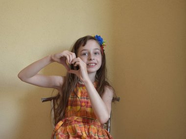 Gri gözleri ve sarı saçlı küçük kız bir sandalyede oturur