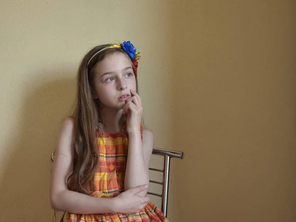Κοριτσάκι με γκρίζα μάτια και ξανθά μαλλιά που κάθεται σε μια καρέκλα — Φωτογραφία Αρχείου