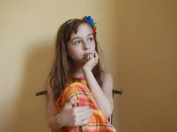 Menina com olhos grisalhos e cabelo loiro senta-se em uma cadeira — Fotografia de Stock