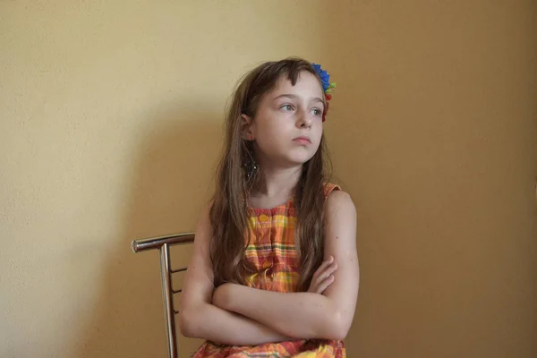 Liten flicka med grå ögon och blont hår sitter på en stol — Stockfoto