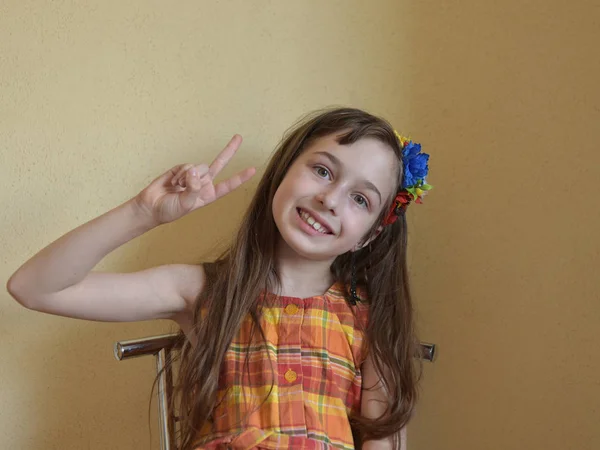 Bambina dagli occhi grigi e dai capelli biondi siede su una sedia — Foto Stock