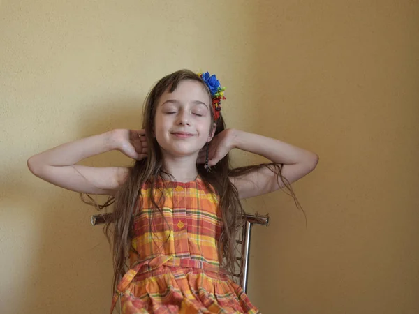 Menina com olhos grisalhos e cabelo loiro senta-se em uma cadeira — Fotografia de Stock