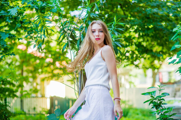 Young beautiful girl posing outdoor, wearing fashionable white dress. Summer style.