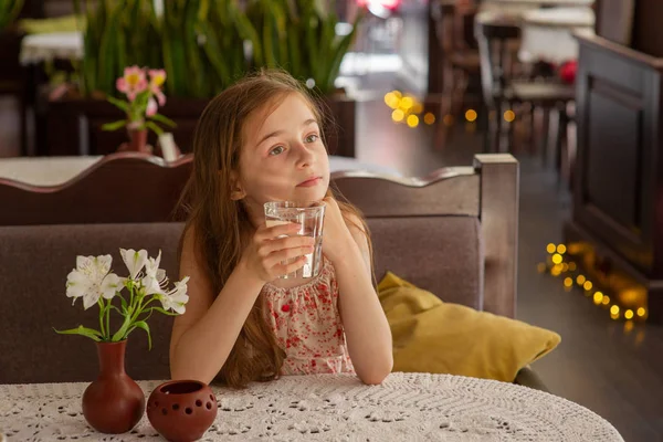 Маленька дівчинка зі склянкою води в кафе . — стокове фото