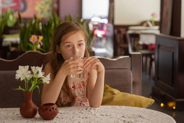 Niña con un vaso de agua en un café . — Foto de Stock