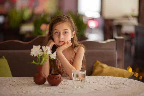 Klein meisje met een glas water in een café. — Stockfoto