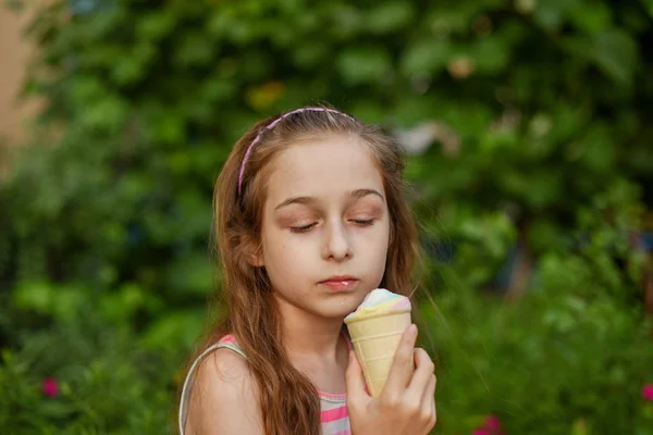 Niña comer helado al aire libre En un vestido brillante a rayas de colores. Soleado verano, clima caluroso . —  Fotos de Stock