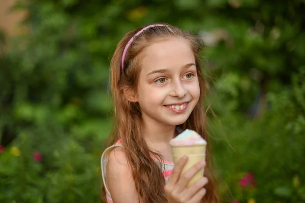 Niña comer helado al aire libre En un vestido brillante a rayas de colores. Soleado verano, clima caluroso . —  Fotos de Stock