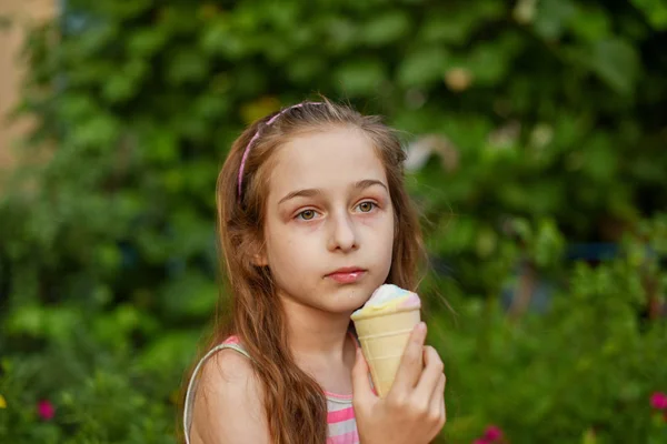 Niña comer helado al aire libre En un vestido brillante a rayas de colores. Soleado verano, clima caluroso . —  Fotos de Stock