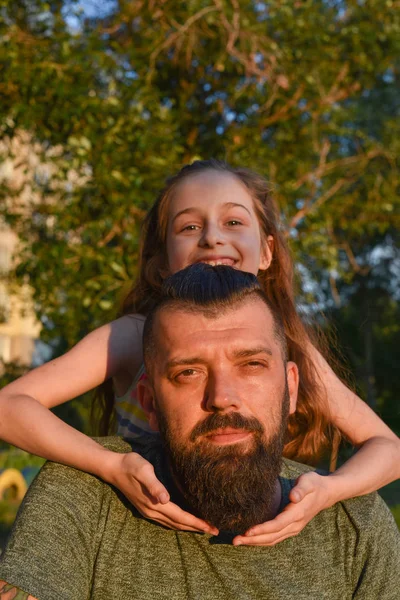 Family time. Little girl hugging her dad with a beard. Summer walk