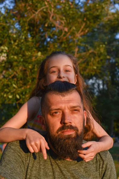 Family time. Little girl hugging her dad with a beard. Summer walk