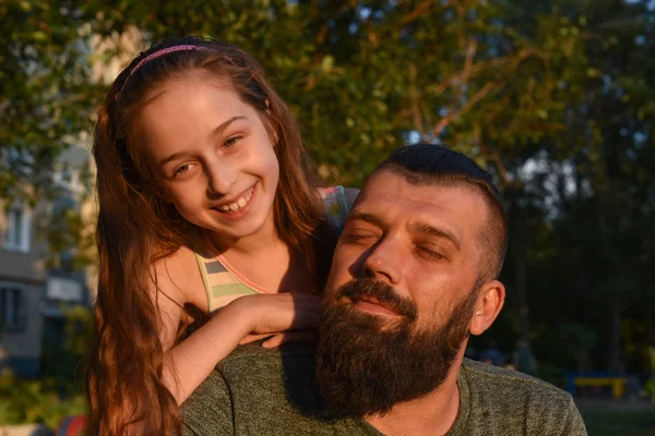 Family time. Little girl hugging her dad with a beard. Summer walk