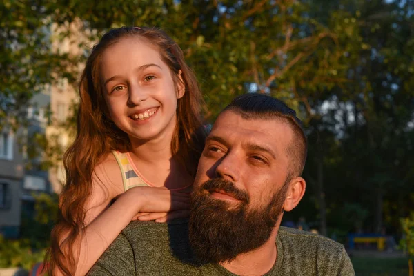 Family time. Little girl hugging her dad with a beard. Summer walk