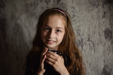 Elinde siyah tişörtlü kahve fincanı tutan küçük bir kız. Tasarımınızı ortaya koymak için mükemmel, alay edin.